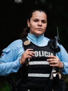A female police officer in uniform standing confidently in an outdoor setting, showcasing law enforcement presence.