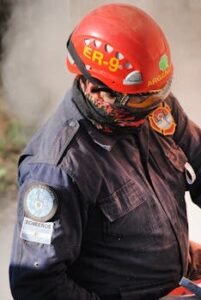 Firefighter in uniform wearing a safety helmet and glasses, preparing for action.